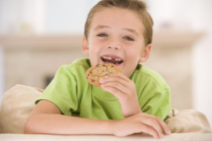 young boy smiling and about to eat cookie