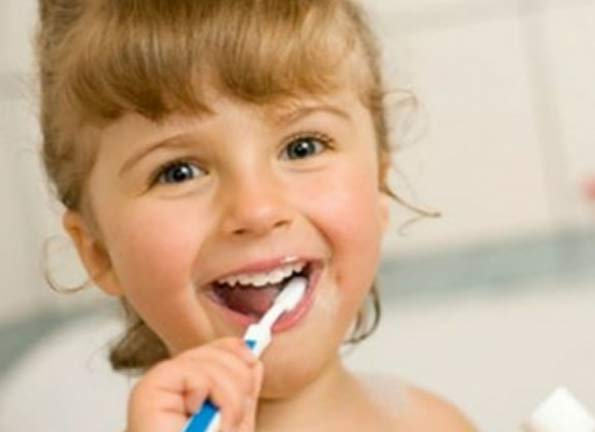 girl brushing her teeth happily
