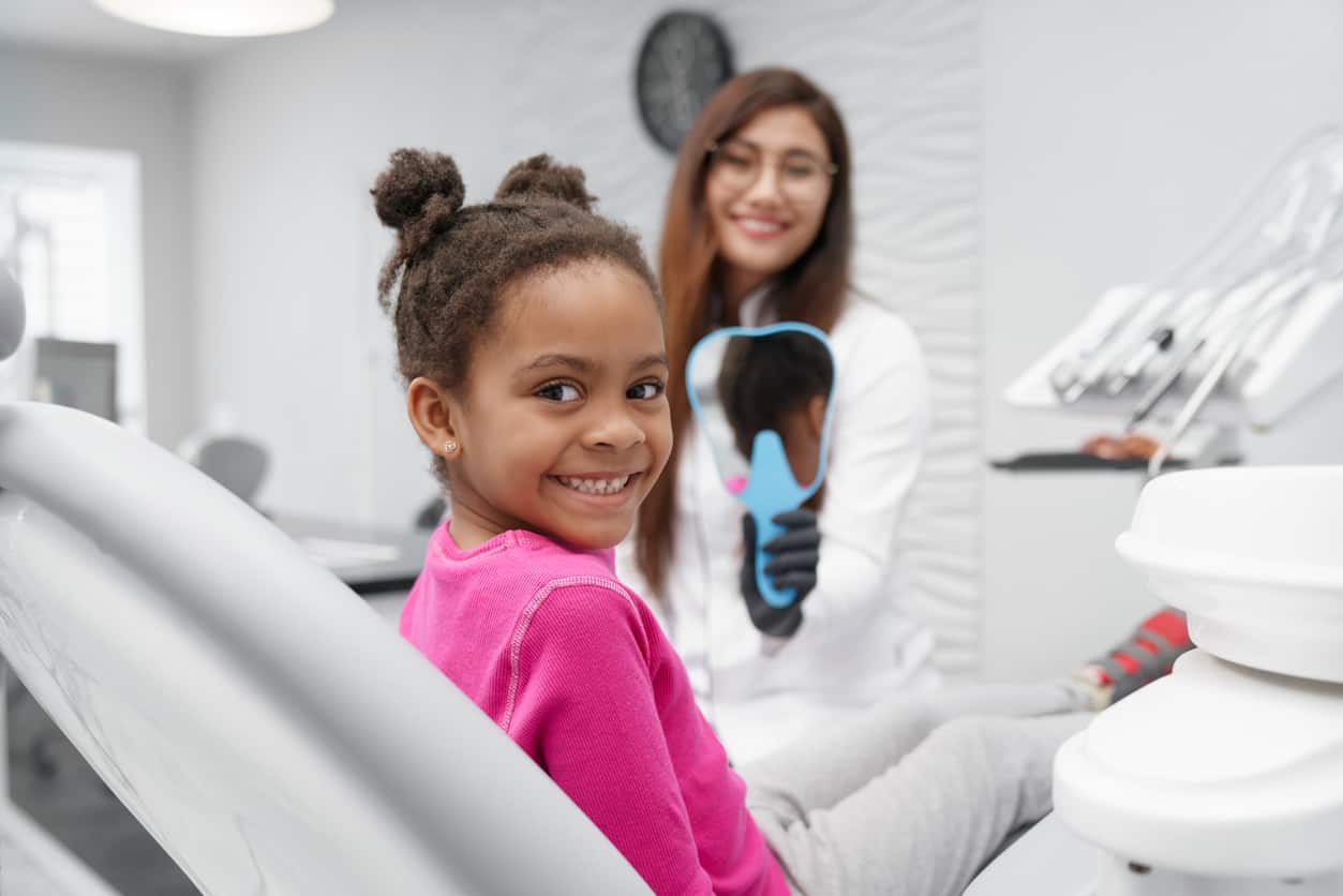child smiling while dentist shows them mirror