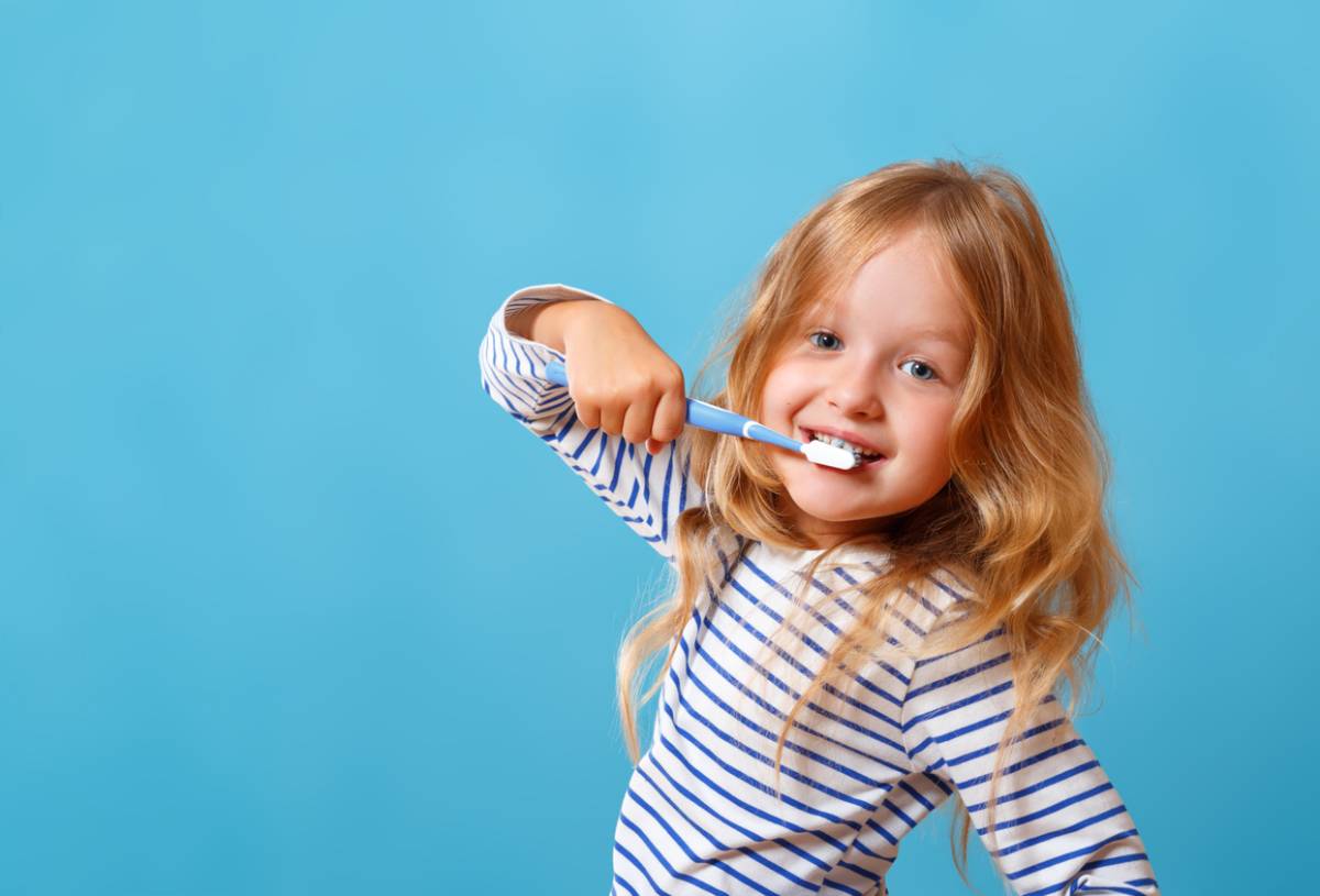 Child brushing her teeth happily.