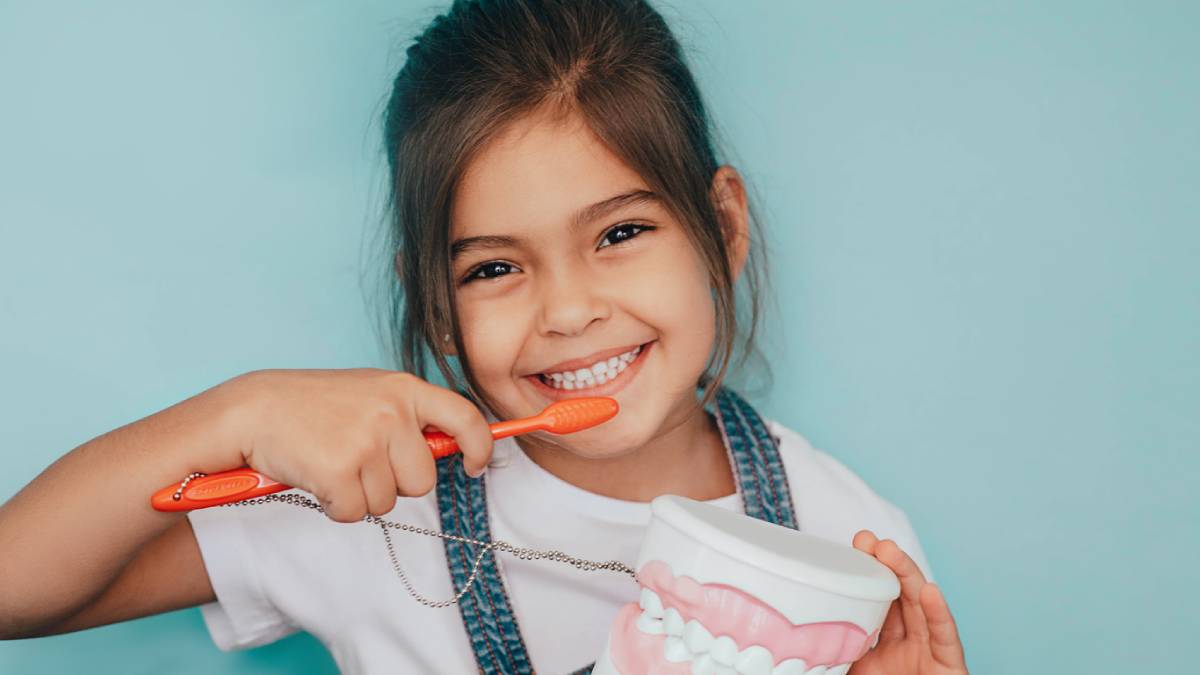 Happy child brushing teeth after visit to kids dentist