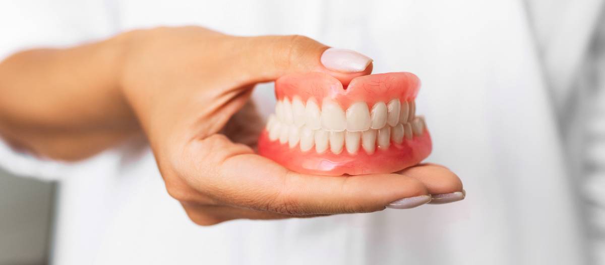 Dentist holding complete dentures in hands.